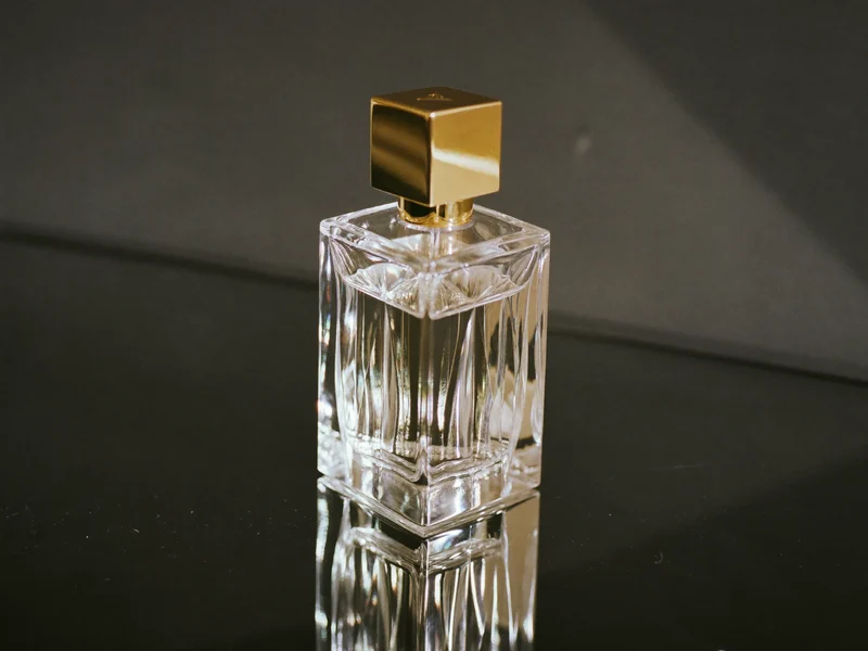 Slebet eau de parfum-flakon med guldtonet hætte på mørk spejloverflade